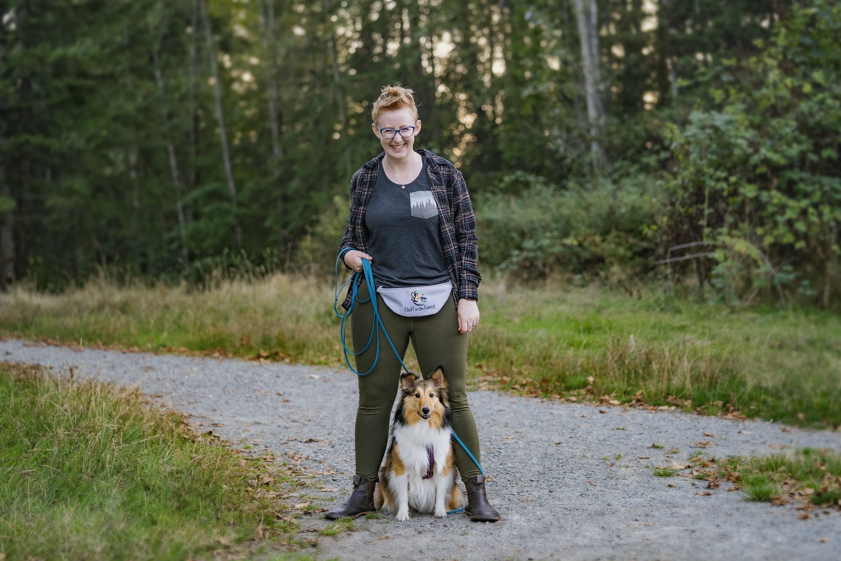 Fluff in the Forest lead trainer Kaeli on the trail with Freya the sheltie on a long line leash